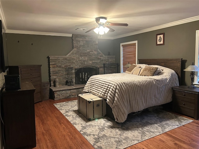 bedroom featuring visible vents, wood finished floors, a fireplace, and ornamental molding