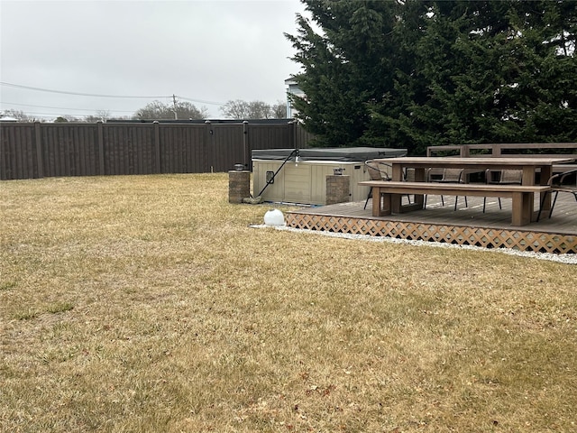 view of yard featuring a wooden deck, fence, and a hot tub