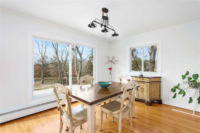 dining room featuring plenty of natural light, light wood-style flooring, ornamental molding, and a baseboard radiator