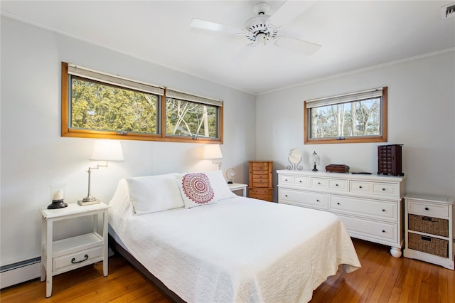 bedroom with multiple windows, visible vents, wood-type flooring, and a baseboard radiator