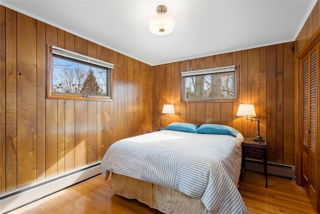 bedroom featuring wooden walls, wood finished floors, and baseboard heating