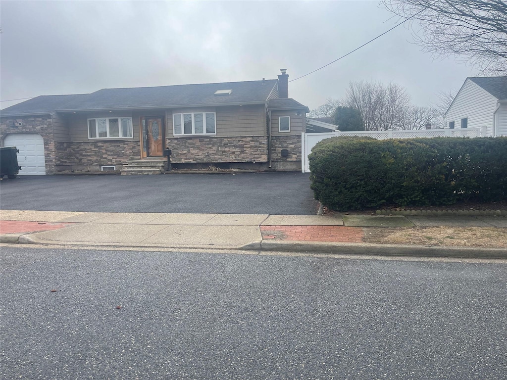 view of front of home with aphalt driveway, stone siding, and an attached garage