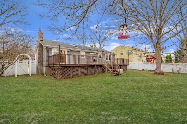 view of yard with a deck, a fenced backyard, and a gate