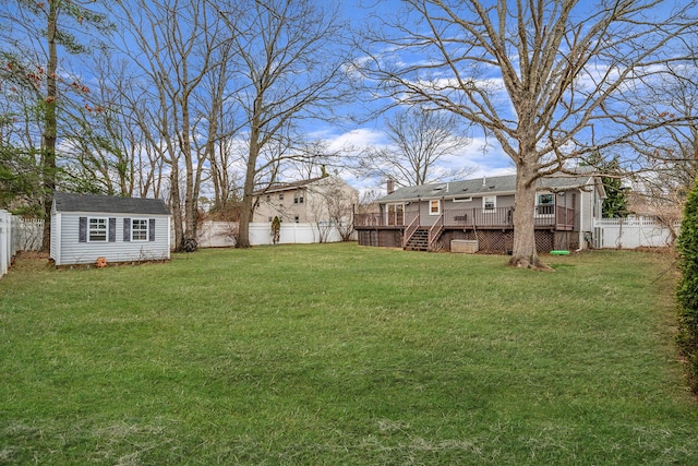 view of yard with an outbuilding, a deck, a fenced backyard, a shed, and stairway