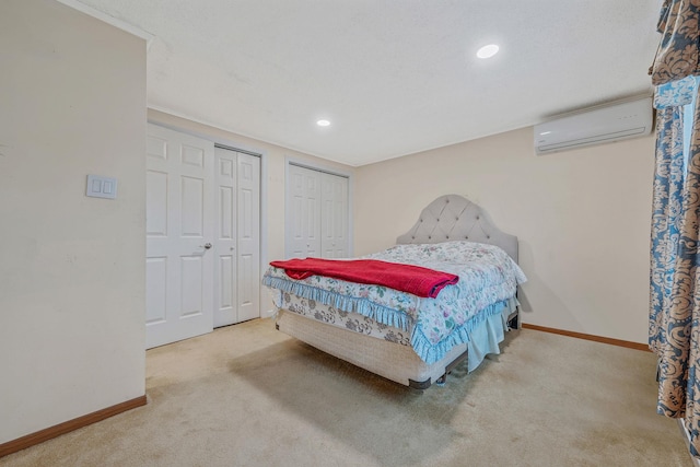 carpeted bedroom featuring recessed lighting, baseboards, two closets, and a wall mounted AC