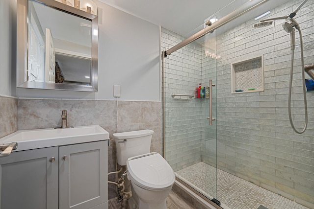 full bathroom with a shower stall, toilet, vanity, wainscoting, and tile walls