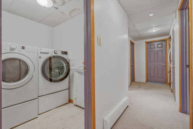 washroom featuring a baseboard heating unit, carpet, washing machine and dryer, laundry area, and tile patterned floors