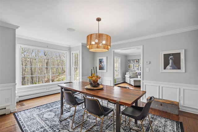 dining area featuring wainscoting, ornamental molding, a baseboard heating unit, and wood finished floors