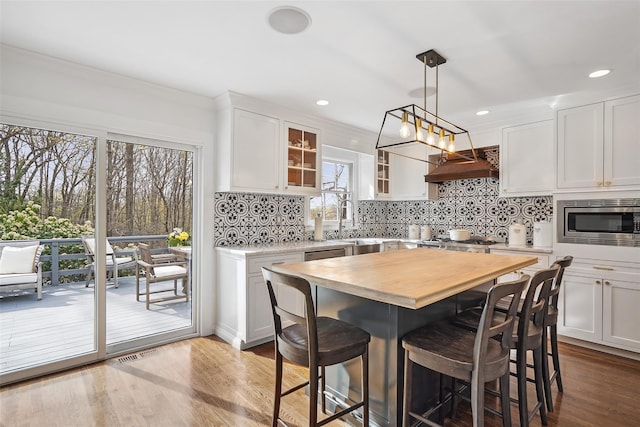 kitchen with tasteful backsplash, a breakfast bar area, stainless steel appliances, and custom exhaust hood