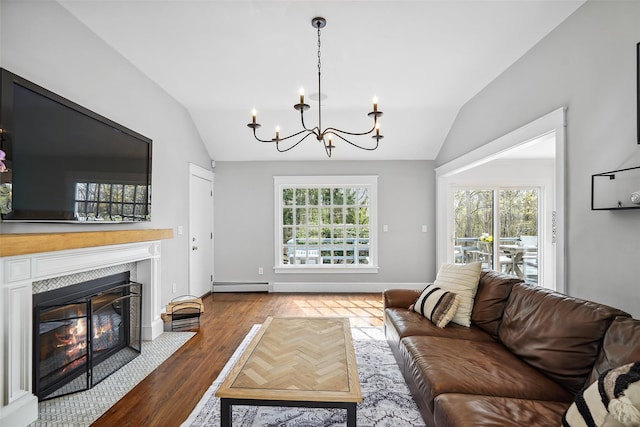 living area featuring baseboard heating, vaulted ceiling, wood finished floors, and a chandelier