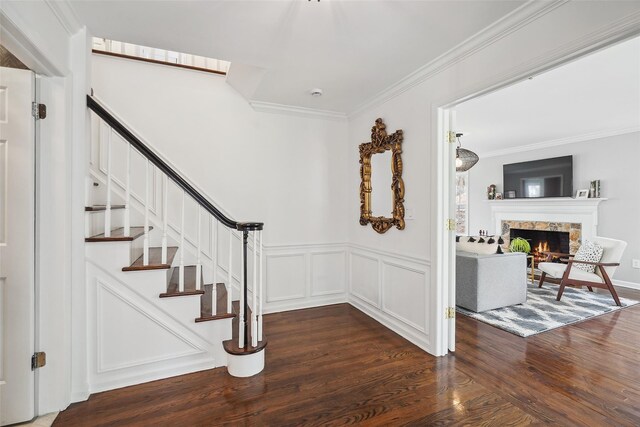 stairway featuring crown molding, a decorative wall, wood finished floors, and a fireplace