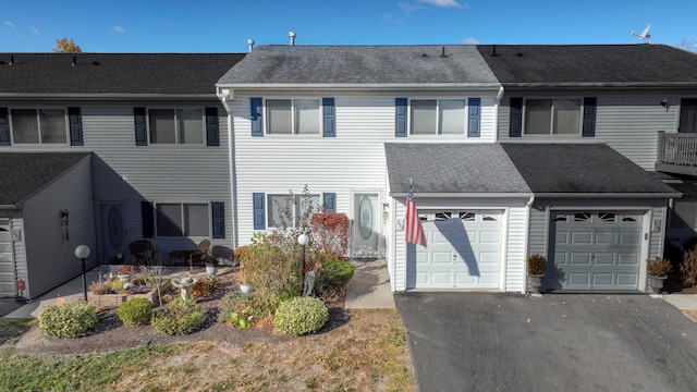 view of front of property with an attached garage, roof with shingles, and driveway