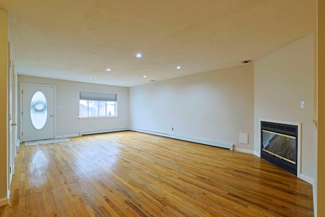 unfurnished living room with baseboards, visible vents, recessed lighting, a glass covered fireplace, and light wood-type flooring