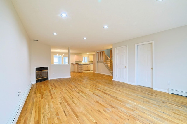 unfurnished living room featuring recessed lighting, stairway, light wood-style floors, a baseboard radiator, and baseboards