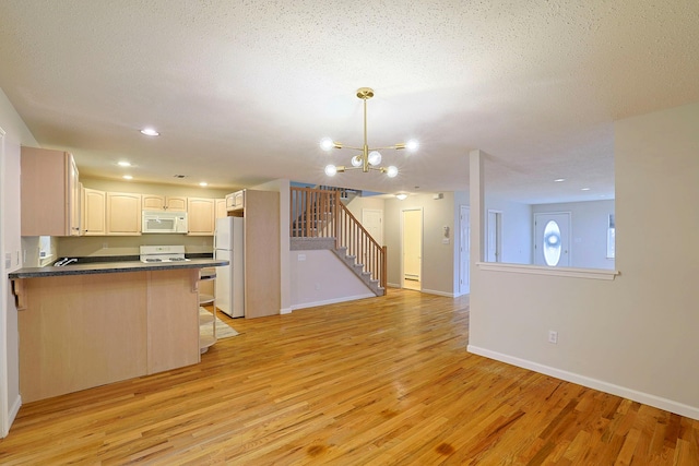 kitchen featuring dark countertops, light wood-style flooring, white appliances, and a peninsula