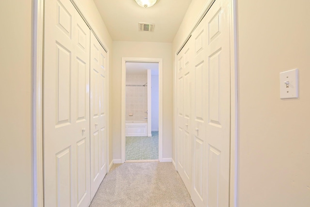 hallway featuring carpet, visible vents, and baseboards