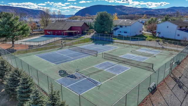 view of tennis court featuring a mountain view and fence