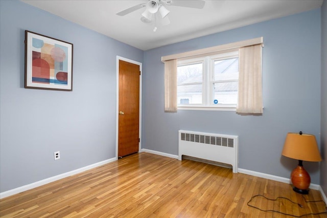 interior space with light wood-type flooring, baseboards, radiator, and ceiling fan