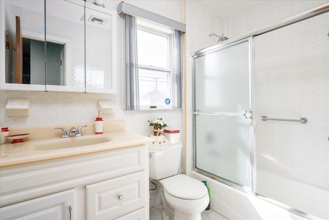 bathroom with visible vents, toilet, combined bath / shower with glass door, tile walls, and decorative backsplash