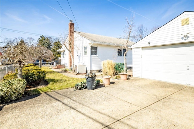 view of front of home with a garage, a chimney, and fence