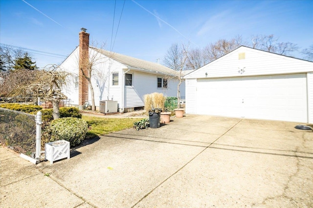 view of side of property featuring a detached garage, fence, central AC unit, a chimney, and an outbuilding