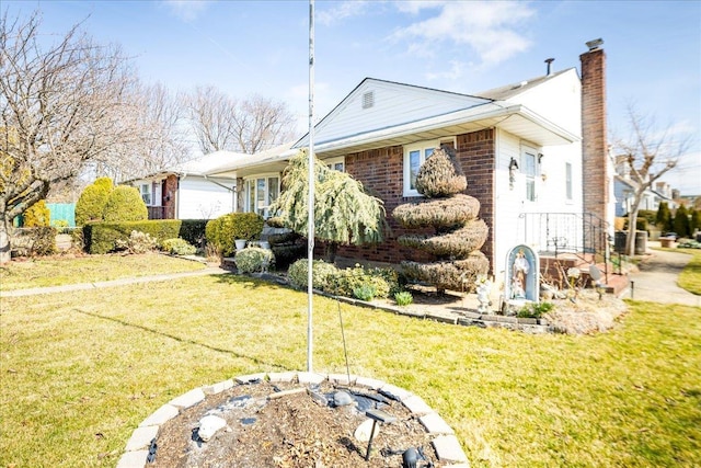 view of side of home with brick siding, a lawn, and a chimney