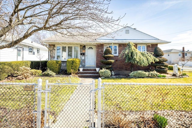 view of front of home featuring a fenced front yard, brick siding, a front yard, and a gate