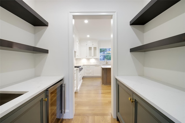 bar with light wood-type flooring, a sink, recessed lighting, wine cooler, and decorative backsplash