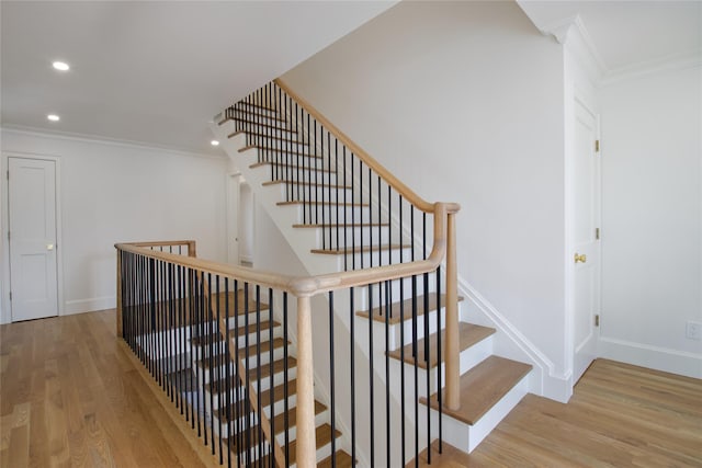 stairs featuring recessed lighting, wood finished floors, baseboards, and ornamental molding