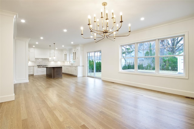 unfurnished living room with baseboards, an inviting chandelier, recessed lighting, a sink, and light wood-type flooring