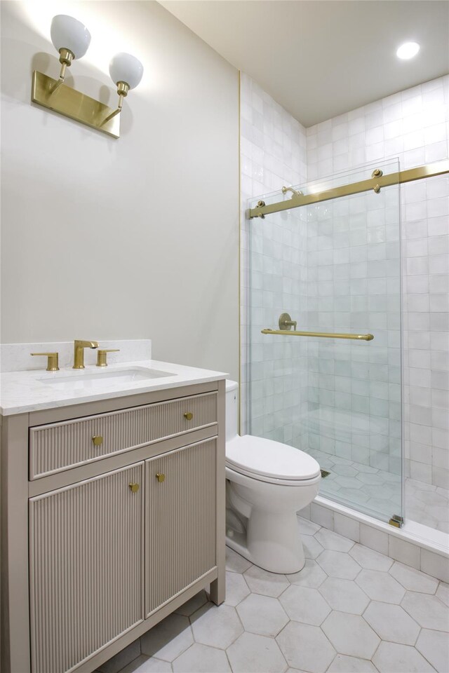 full bath with toilet, a stall shower, vanity, and tile patterned flooring