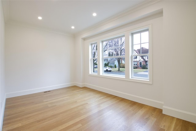 empty room featuring crown molding, light wood-style flooring, recessed lighting, and baseboards