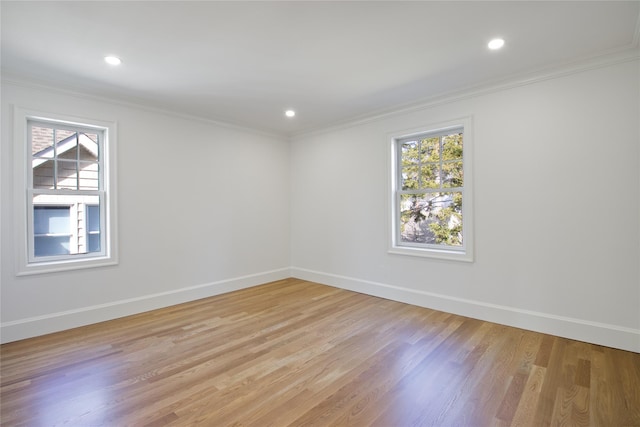 unfurnished room featuring light wood finished floors, crown molding, and baseboards