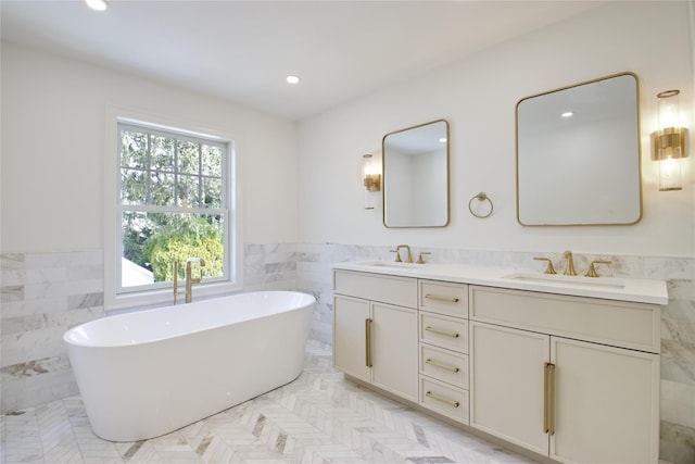 bathroom with a sink, a wainscoted wall, a soaking tub, and double vanity