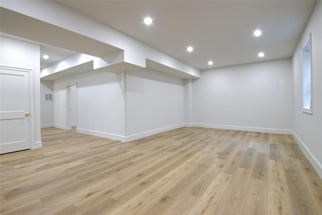 finished below grade area with visible vents, recessed lighting, light wood-type flooring, and baseboards