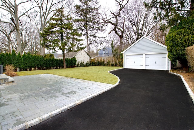 view of yard featuring a garage, a patio, and an outbuilding