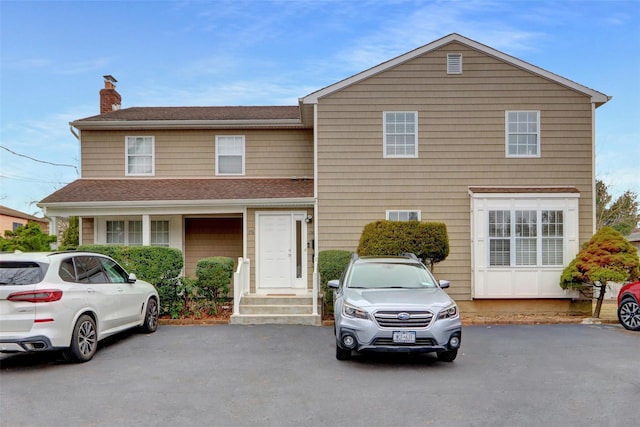 traditional-style home with a chimney and a shingled roof