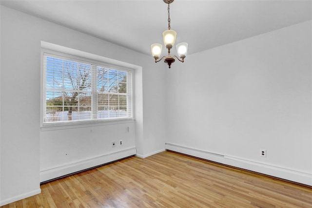 unfurnished room featuring light wood-type flooring, a baseboard radiator, baseboards, and a notable chandelier