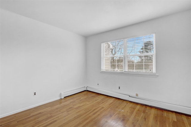 spare room with baseboard heating, baseboards, and light wood-style floors