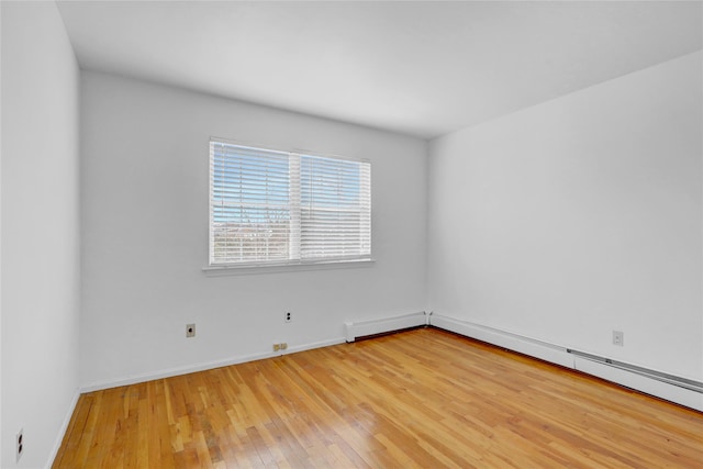 spare room with light wood finished floors, a baseboard heating unit, and baseboards