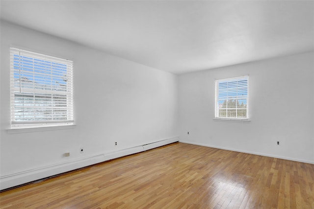 empty room featuring light wood-style flooring, baseboards, and baseboard heating