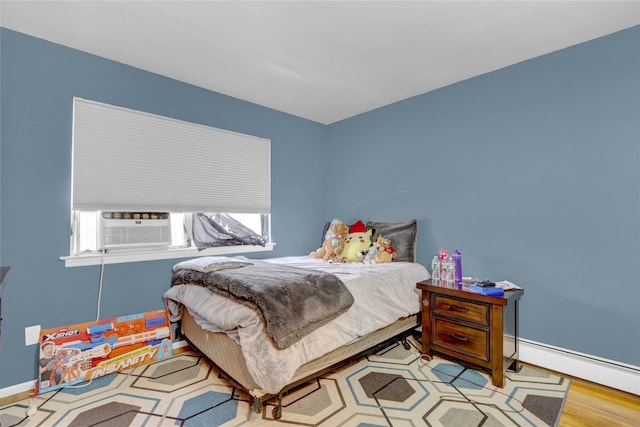 bedroom with wood finished floors, baseboards, and a baseboard radiator