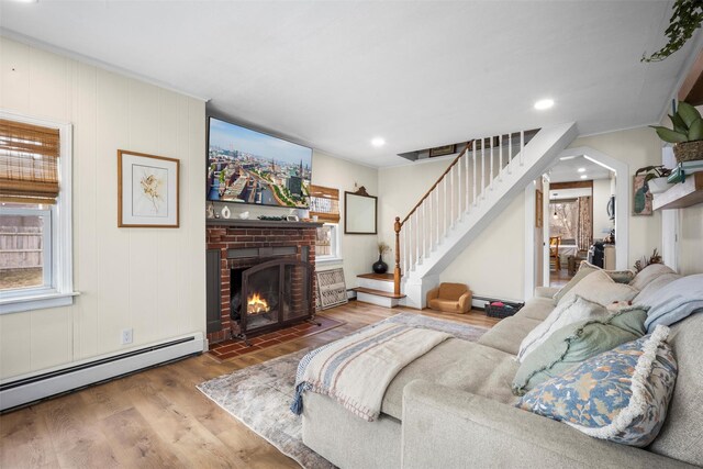 living area with wood finished floors, recessed lighting, stairs, a baseboard heating unit, and a brick fireplace