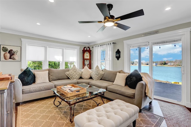 living room with recessed lighting, ceiling fan, ornamental molding, light wood-style floors, and a water view