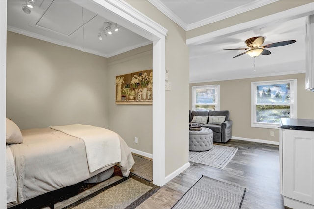 bedroom featuring attic access, crown molding, baseboards, and wood finished floors