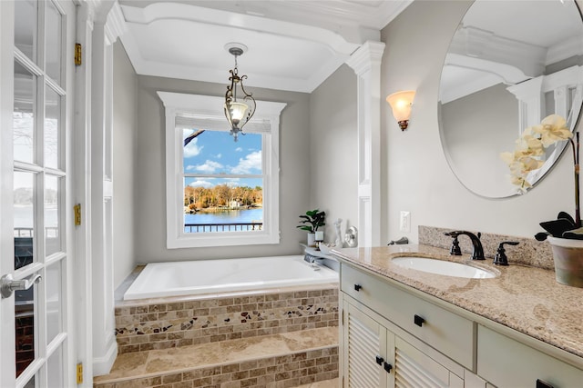 bathroom with ornate columns, a garden tub, vanity, and crown molding