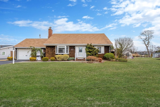 view of front of house with a front yard, roof with shingles, driveway, an attached garage, and a chimney