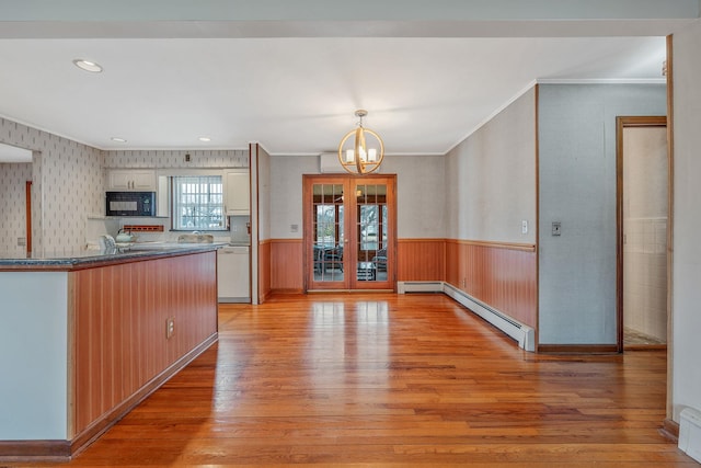 kitchen featuring an inviting chandelier, light wood-style floors, black microwave, wainscoting, and dishwasher