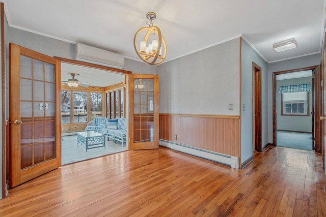 unfurnished dining area with an AC wall unit, french doors, wood-type flooring, wainscoting, and baseboard heating