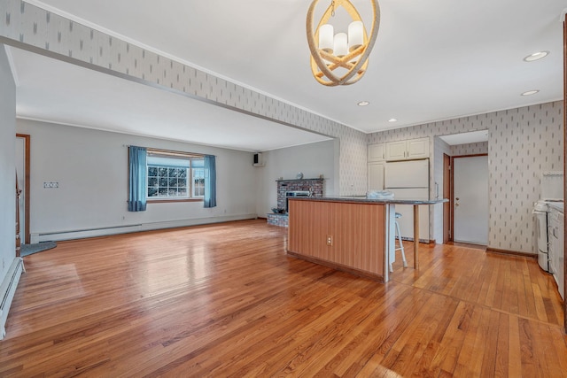 kitchen featuring freestanding refrigerator, an inviting chandelier, light wood finished floors, a baseboard radiator, and stove